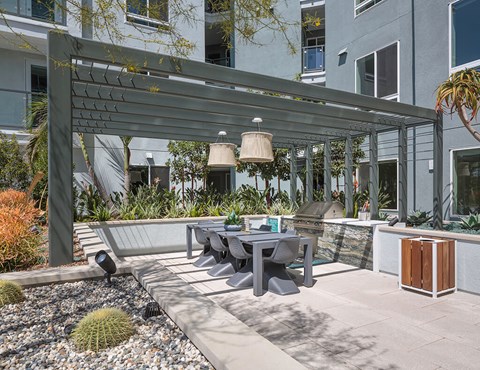 A patio with a table and chairs under a pergola.