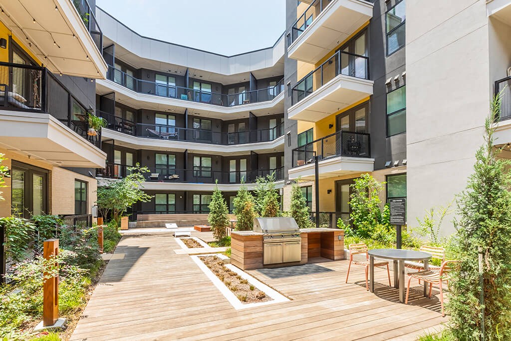 a courtyard with a barbecue and tables in a modern apartment building