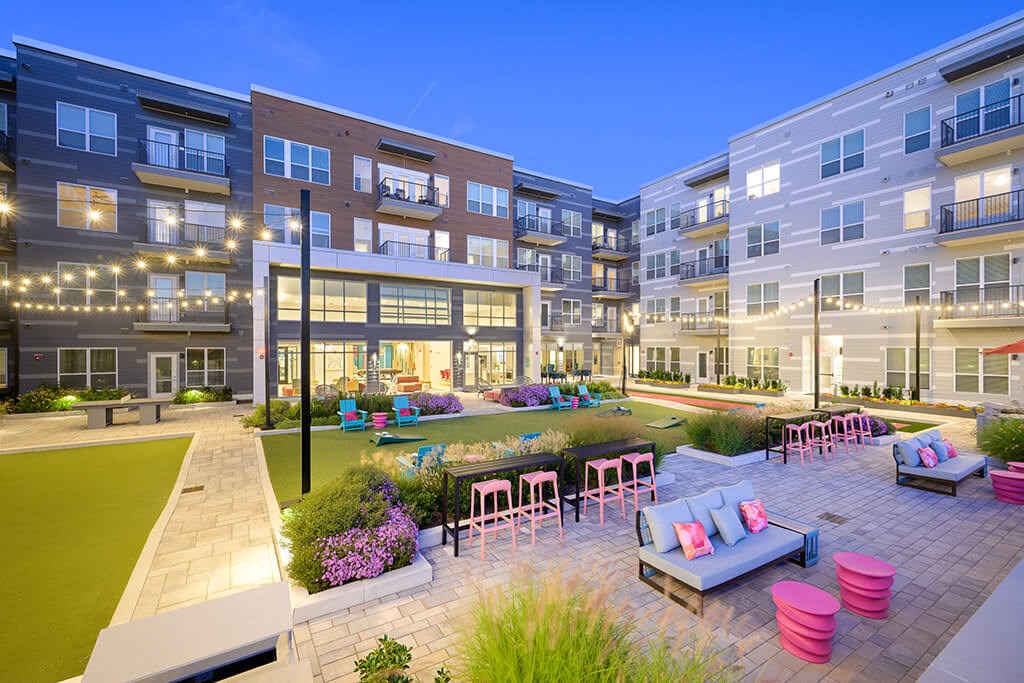 a rendering of an apartment complex with a courtyard and tables and chairs