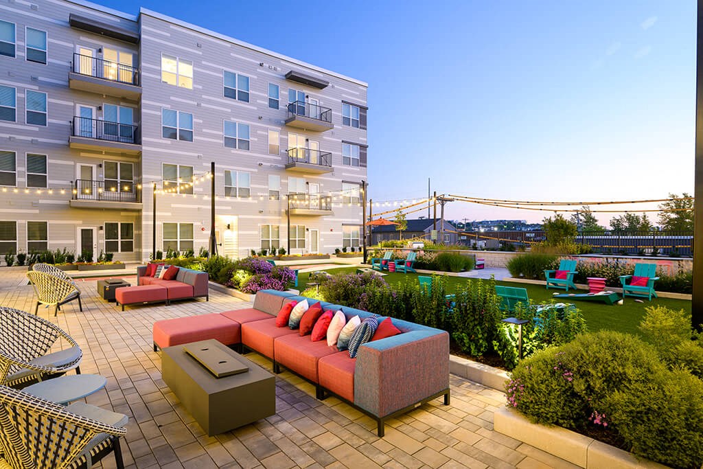 a patio with couches and a table in front of a building