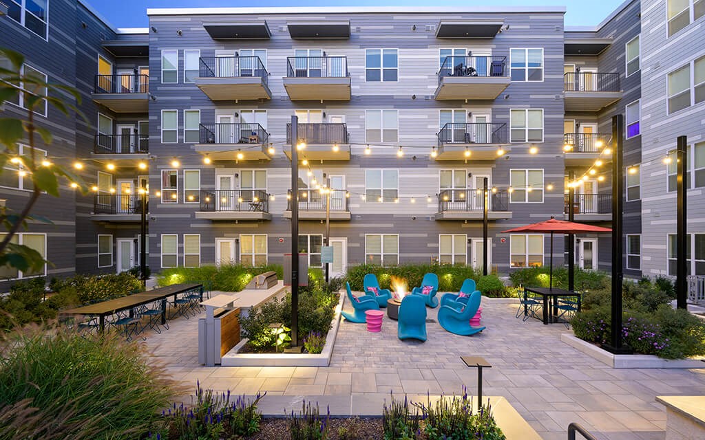 an outdoor area with chairs and tables in front of an apartment building