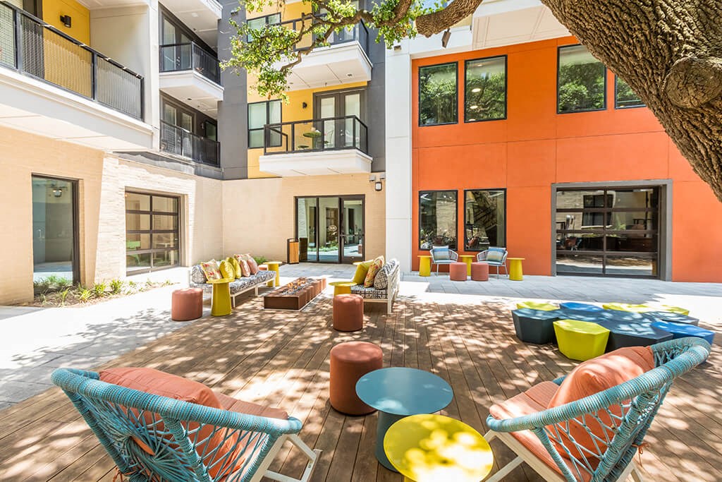 a courtyard with chairs and tables in front of a building