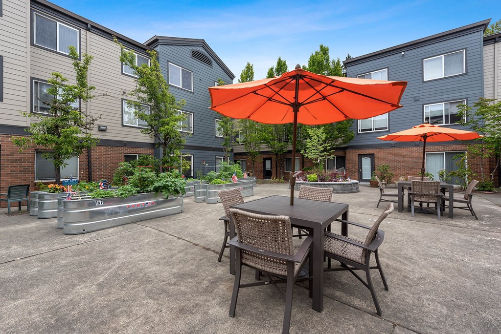 Dog-Friendly Apartments in Federal Way WA - Meridian Court - Multiple Seating Area, Planted Garden, Umbrella Shaded Areas, and Building Exterior