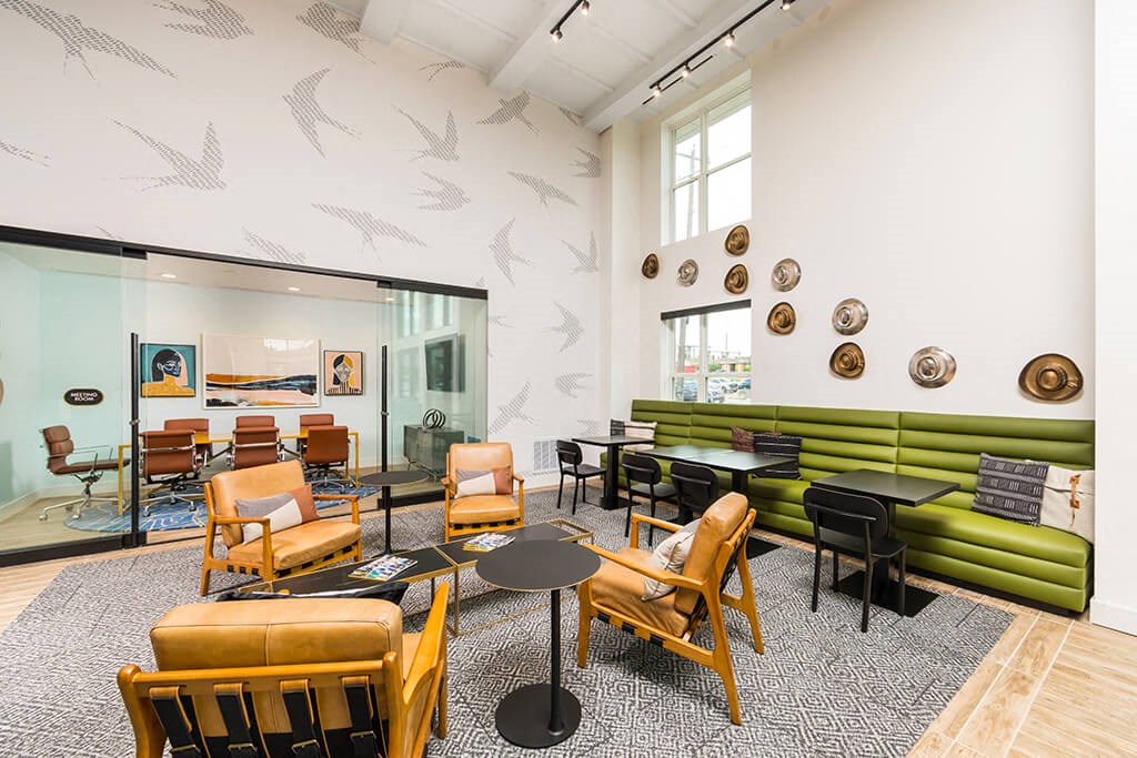 a lounge area with chairs and tables and a large window