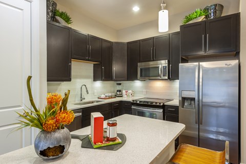 A kitchen with a white counter top and black cabinets.