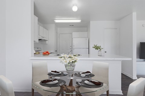 A modern dining room with a glass table and white chairs.