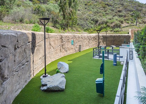 A park with a stone wall and a green lawn.