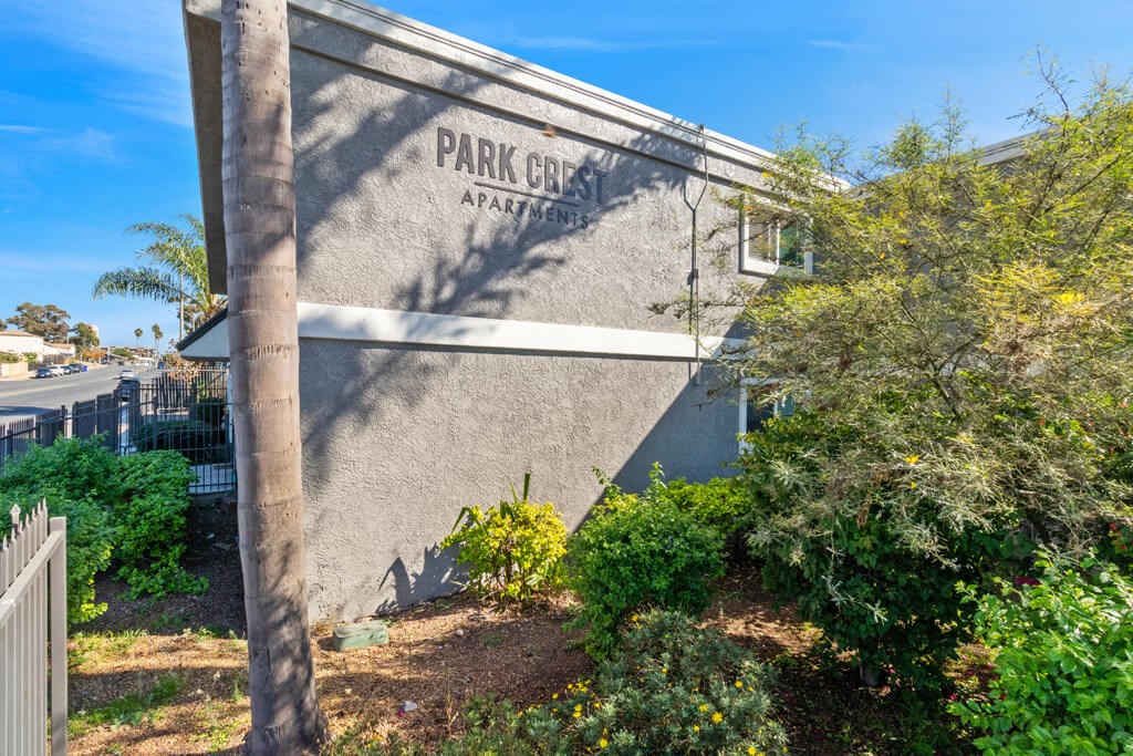 the side of a park city apartments building with trees and bushes