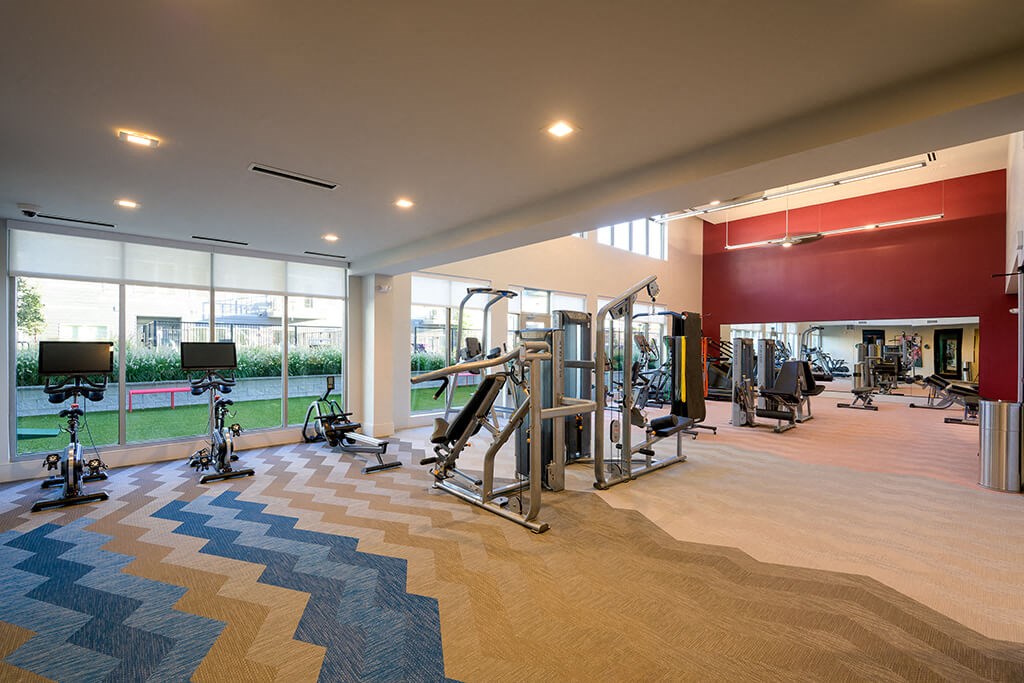 a gym with weights and other exercise equipment in a building with large windows
