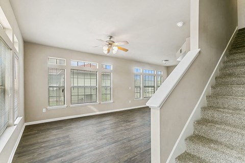 a living room with a ceiling fan and a staircase