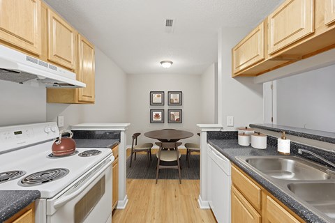 A kitchen with a white stove and wooden cabinets.