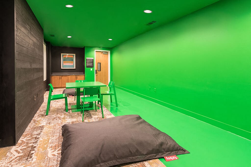 a green conference room with a table and a bed