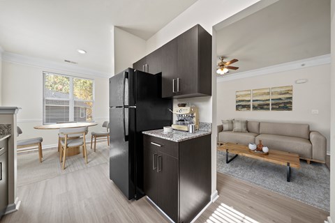 A black refrigerator is in the middle of a kitchen with a table and chairs.