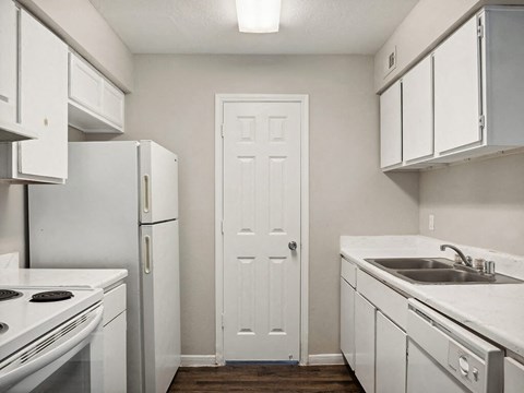 a kitchen with white appliances and a white door