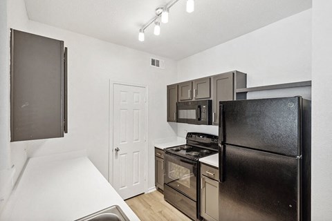 a kitchen with stainless steel appliances and a black refrigerator
