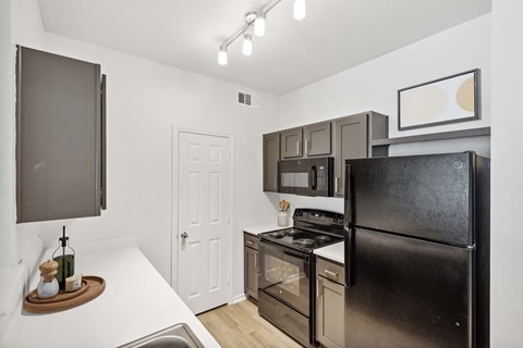 A black refrigerator is in a kitchen with a white door.