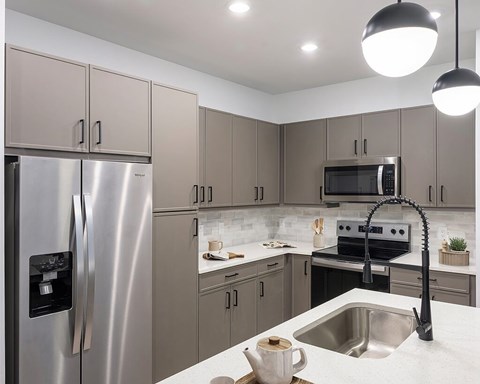 A modern kitchen with a stainless steel refrigerator and a black faucet.