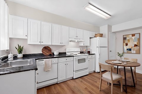 A kitchen with white cabinets and a black countertop.