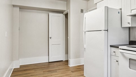 an empty kitchen with white appliances and a refrigerator