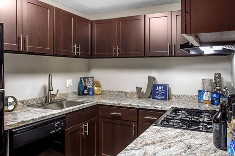 A kitchen with brown cabinets and granite countertops.