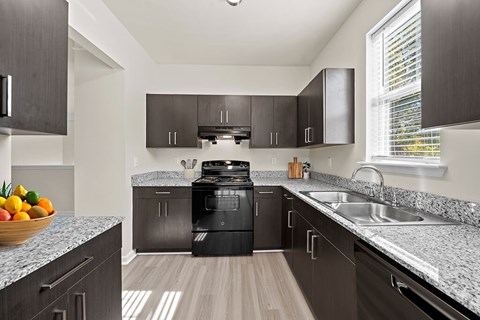 A modern kitchen with dark wood cabinets and granite countertops.