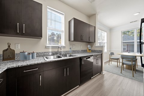 A kitchen with dark brown cabinets and a granite countertop.