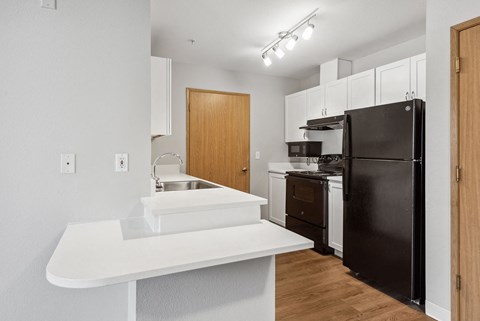 a kitchen with a white counter top and a black refrigerator