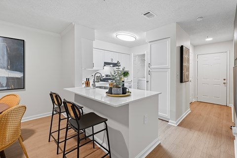 A kitchen with a white counter and black chairs.