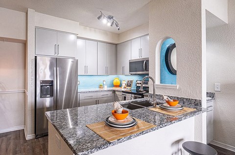 A kitchen with a granite counter top and stainless steel appliances.