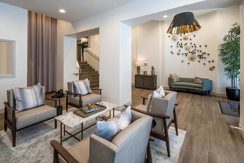 A living room with a staircase in the background and a couch with a pillow on it.