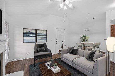 A living room with a grey couch, a black chair, a coffee table, and a painting on the wall.