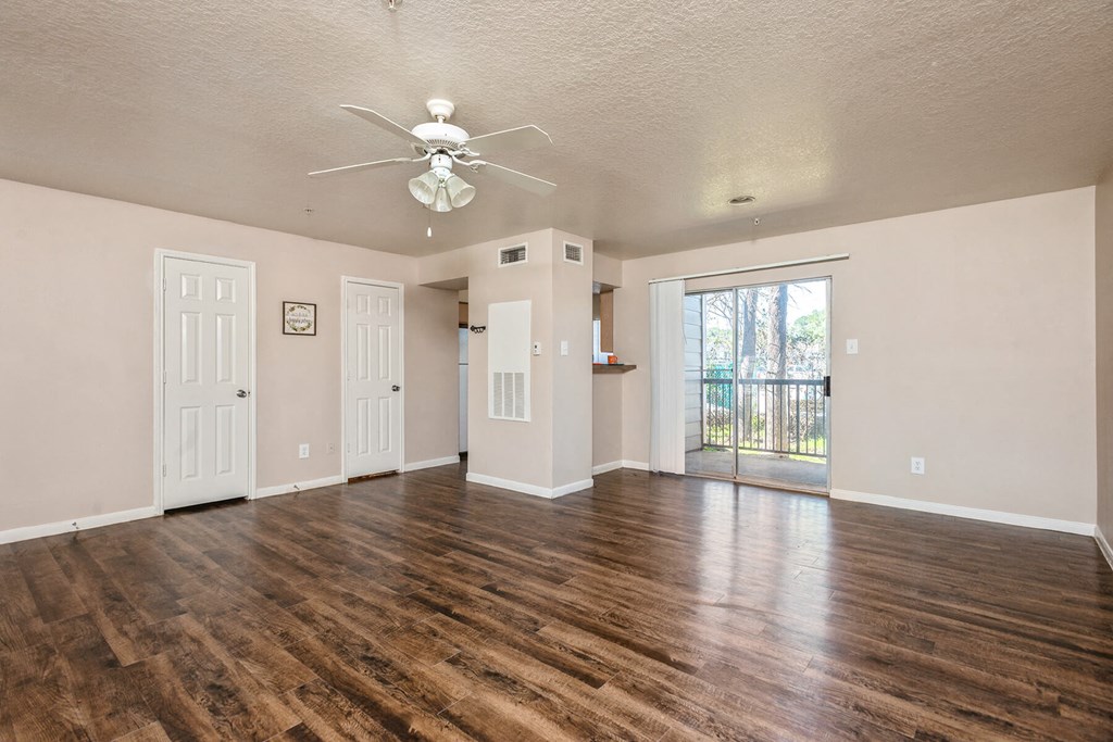 Living room with ceiling fan and hardwood flooring at Park Village Apartments in Conroe TX