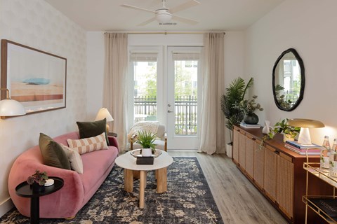 A living room with a pink couch, a coffee table, and a painting on the wall.