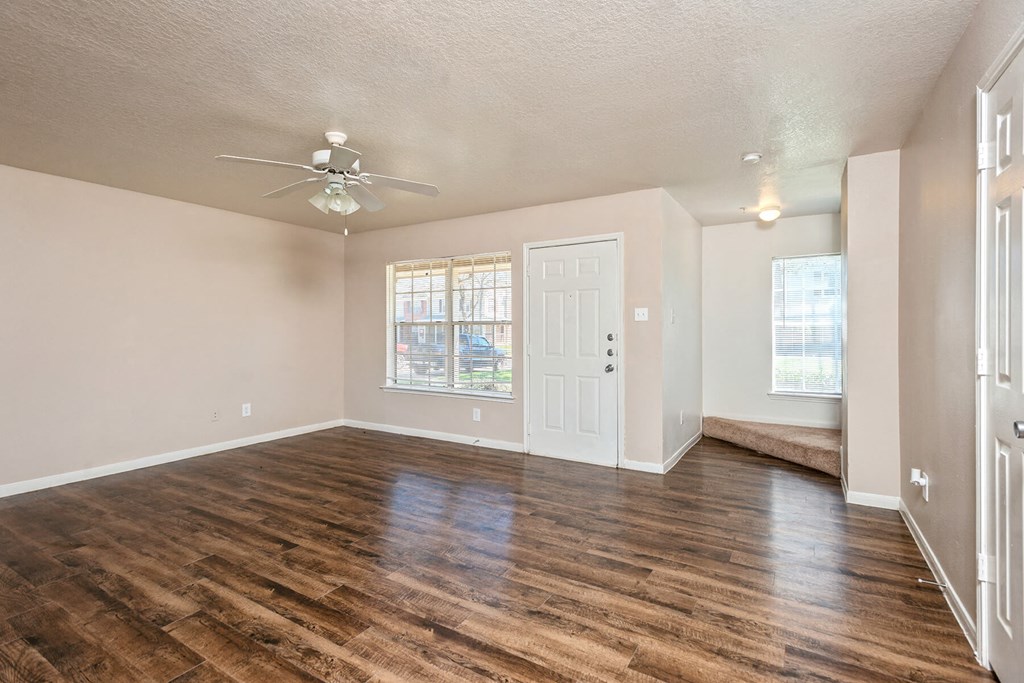 Living room with hardwood flooring and ceiling fan at Park Village Apartments in Conroe TX