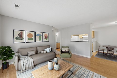 A living room with a grey couch, a green chair, a wooden coffee table and a painting on the wall.