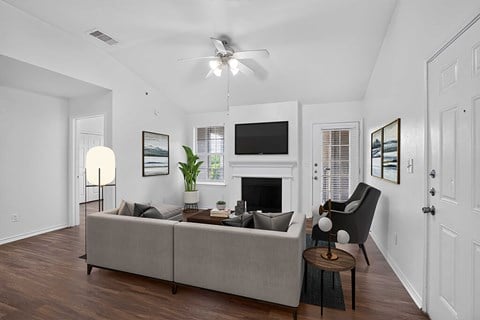 A living room with a grey couch, a fireplace, and a television.