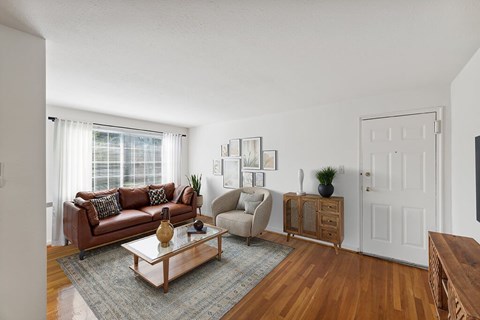 A living room with a brown couch, a white door, and a wooden floor.