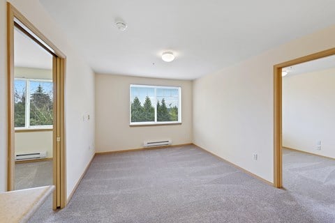 a spacious living room with carpet and a window