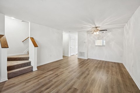 a living room with white walls and a ceiling fan