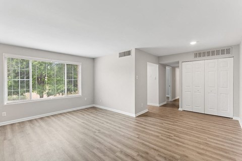 an empty living room with a large window and white doors