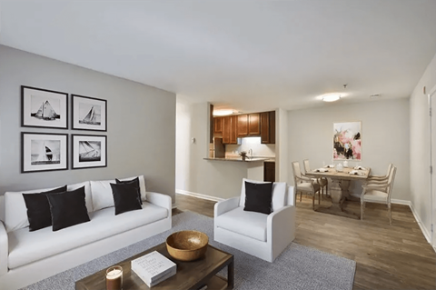A living room with a white couch and a coffee table with a book and a candle on it.