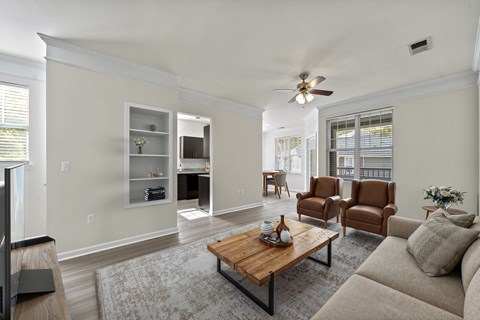 A living room with a brown coffee table and two brown chairs.