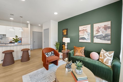 A living room with a green couch, a wooden table, and a pineapple on the table.
