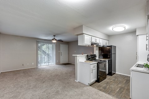A white kitchen with a black refrigerator and a fan on the ceiling.