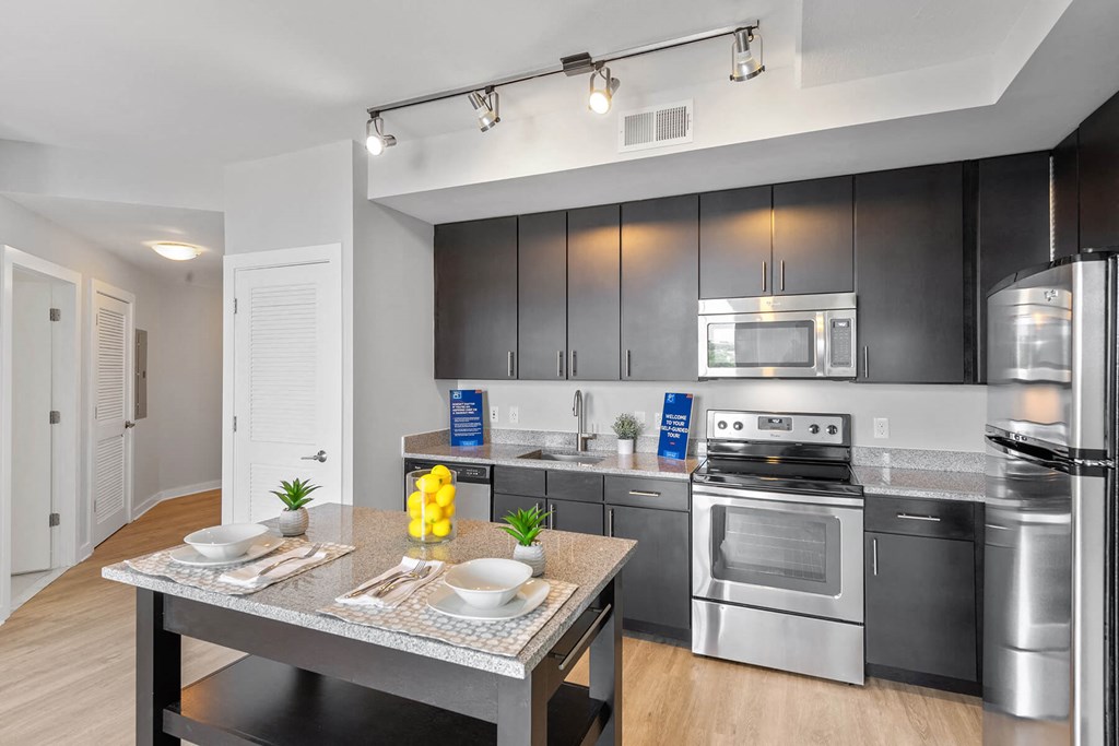 Kitchen with track lighting and island at Bradley Braddock Road Station Apartments in Alexandria VA
