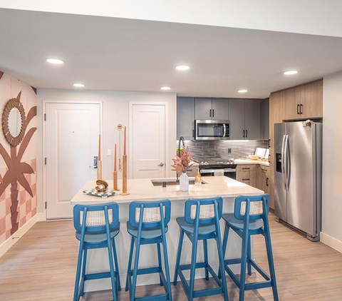 A kitchen with a white counter and blue bar stools.