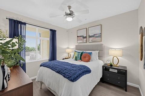 A bedroom with a bed, nightstand, and a ceiling fan.