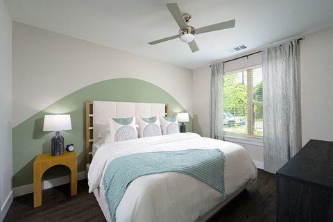 a bedroom with a green accent wall and a white bed with a tufted headboard at Verge Apartments in Atlanta, GA