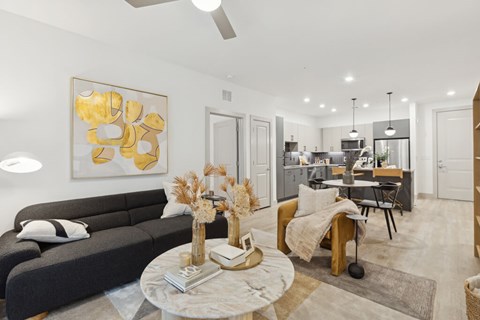 A modern living room with a grey sofa, a coffee table, and a painting on the wall.
