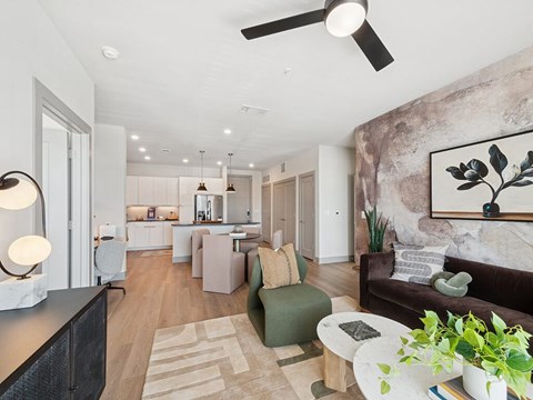 A modern living room with a brown couch and a large painting on the wall.